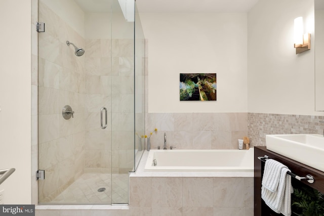 full bathroom featuring vanity, a bath, and a shower stall