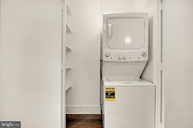 clothes washing area featuring stacked washer and dryer, laundry area, and dark wood-type flooring