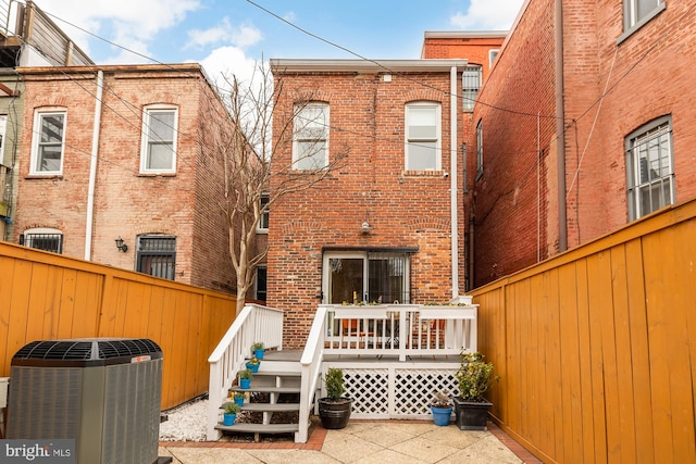 rear view of house featuring central AC, brick siding, a fenced backyard, and a wooden deck