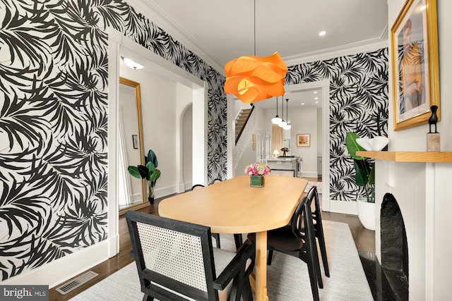 dining area with arched walkways, dark wood finished floors, visible vents, stairway, and ornamental molding