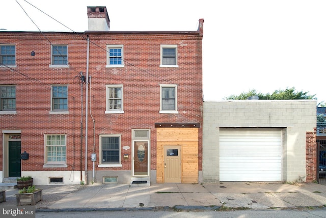 view of front of property with a garage, brick siding, and a chimney