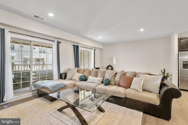 living area with light wood-type flooring, visible vents, and recessed lighting