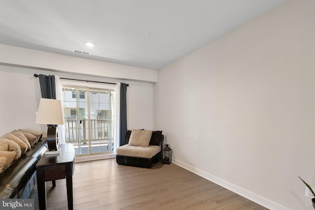 living area with visible vents, baseboards, and wood finished floors