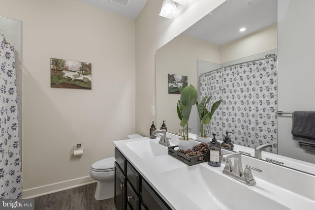 bathroom featuring baseboards, toilet, wood finished floors, curtained shower, and a sink