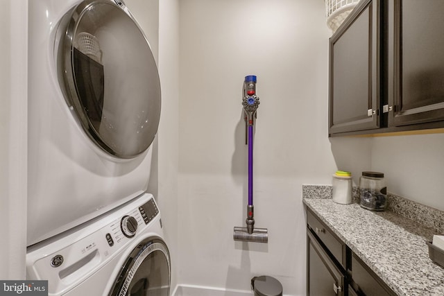 washroom featuring cabinet space and stacked washing maching and dryer