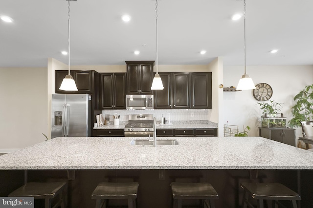 kitchen with stainless steel appliances, a spacious island, backsplash, dark brown cabinetry, and a kitchen bar