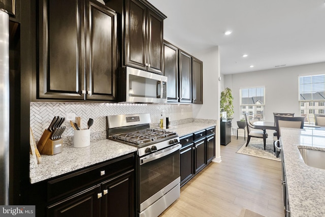 kitchen featuring recessed lighting, appliances with stainless steel finishes, light wood-type flooring, backsplash, and light stone countertops