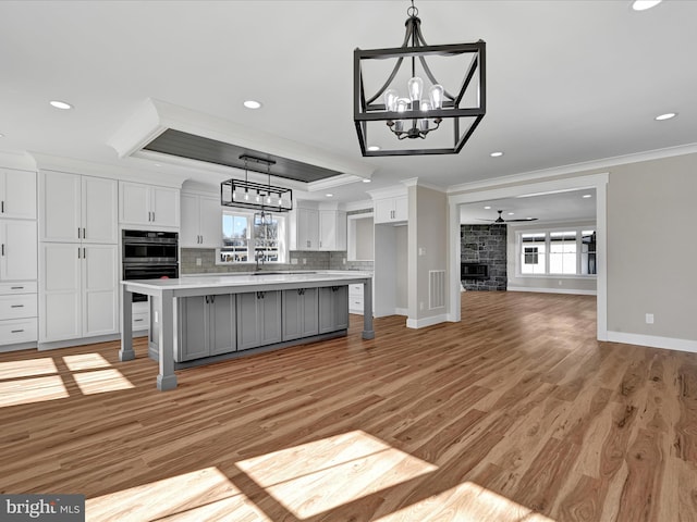 kitchen featuring a tray ceiling, a kitchen island, white cabinetry, and a kitchen bar