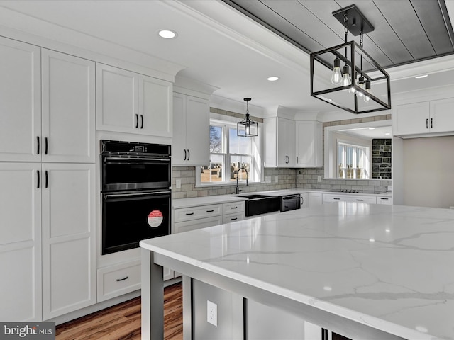 kitchen featuring sink, light stone counters, and white cabinets