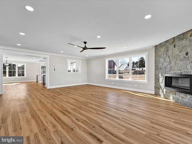 unfurnished living room featuring ceiling fan, light wood-type flooring, crown molding, and a fireplace