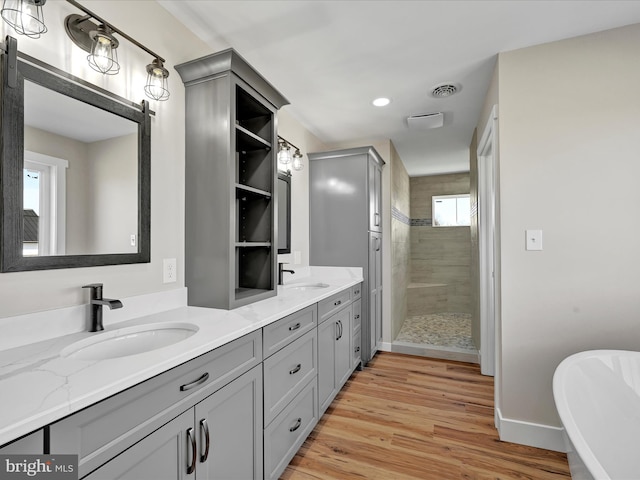 bathroom featuring wood-type flooring, plus walk in shower, and vanity