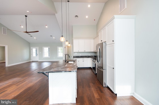 kitchen with hanging light fixtures, open floor plan, a kitchen island with sink, white cabinetry, and a sink