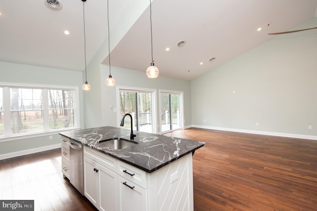 kitchen featuring visible vents, dark stone counters, open floor plan, a kitchen island with sink, and a sink