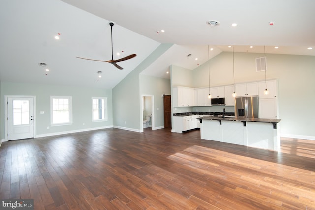 kitchen featuring pendant lighting, a center island with sink, stainless steel appliances, open floor plan, and white cabinets