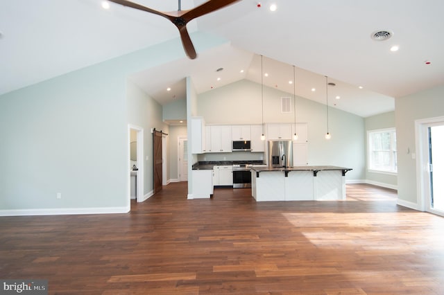 kitchen featuring stainless steel appliances, dark countertops, hanging light fixtures, white cabinets, and a kitchen island