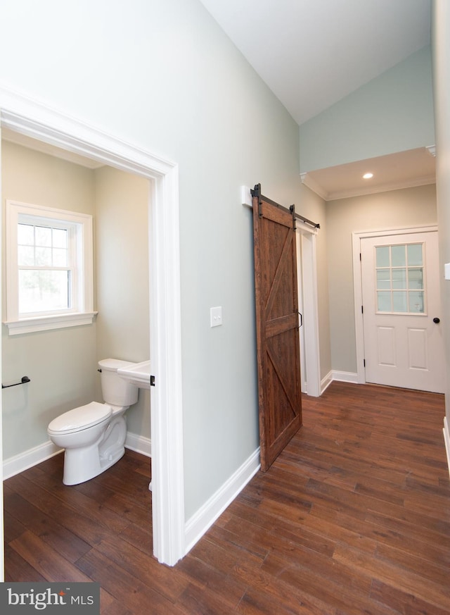 half bathroom with baseboards, vaulted ceiling, toilet, and wood finished floors