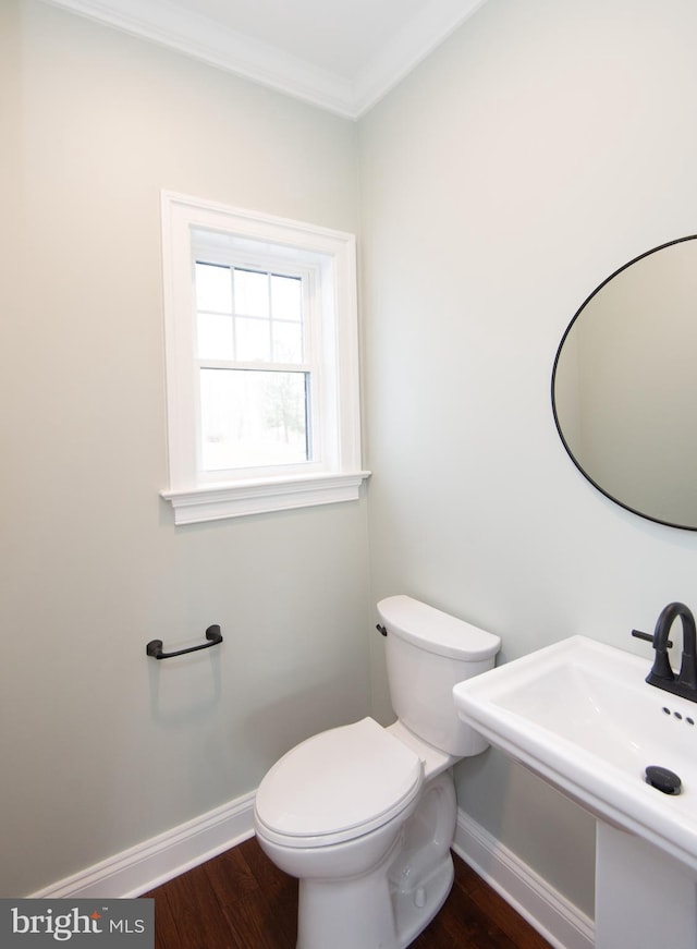 bathroom with a sink, baseboards, crown molding, and wood finished floors