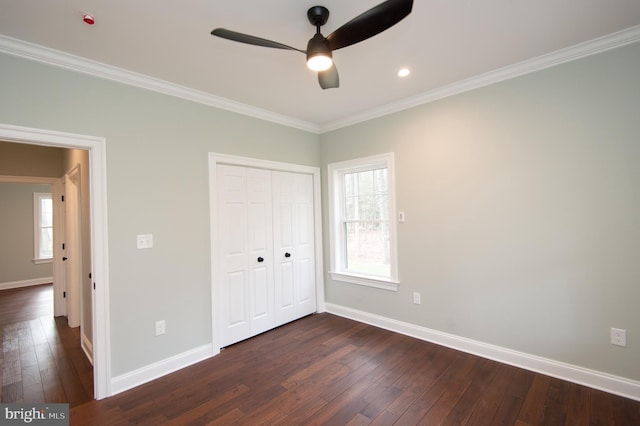 unfurnished bedroom with baseboards, dark wood-style flooring, a closet, and crown molding