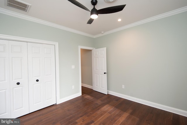 unfurnished bedroom featuring baseboards, visible vents, dark wood-type flooring, crown molding, and a closet