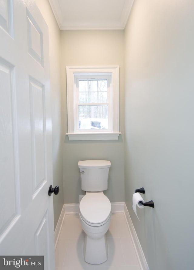 bathroom with tile patterned flooring, baseboards, crown molding, and toilet