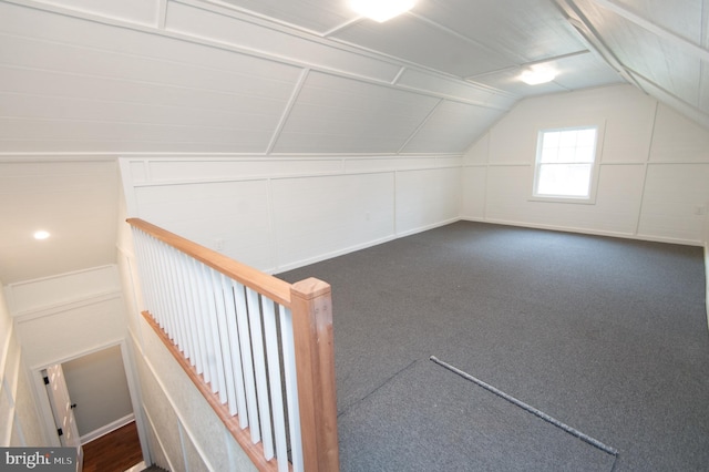 additional living space featuring lofted ceiling and dark colored carpet