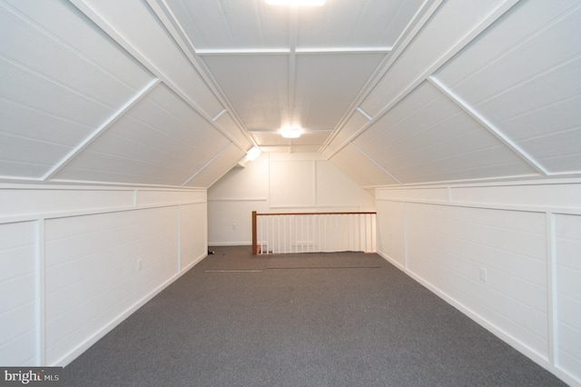 additional living space featuring vaulted ceiling and dark colored carpet