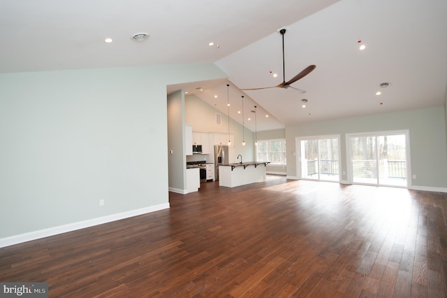 unfurnished living room featuring baseboards, dark wood-style floors, ceiling fan, high vaulted ceiling, and recessed lighting