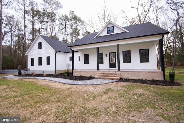 modern farmhouse style home with a porch, a front lawn, and a shingled roof