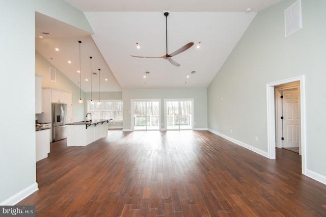 unfurnished living room with ceiling fan, dark wood-style flooring, a sink, visible vents, and baseboards