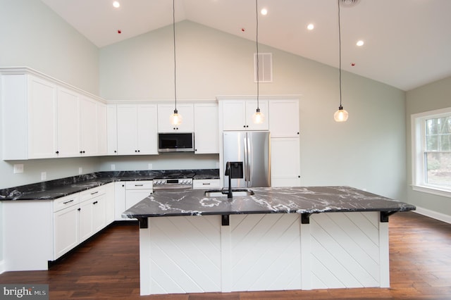 kitchen featuring appliances with stainless steel finishes, dark stone counters, a sink, and a large island