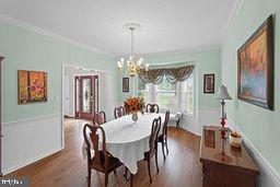 dining space with a notable chandelier, crown molding, and dark hardwood / wood-style floors