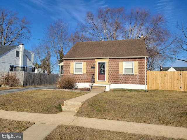 bungalow-style home featuring brick siding, roof with shingles, a front yard, and fence