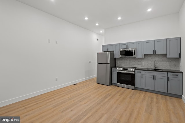 kitchen featuring gray cabinets, appliances with stainless steel finishes, sink, and tasteful backsplash