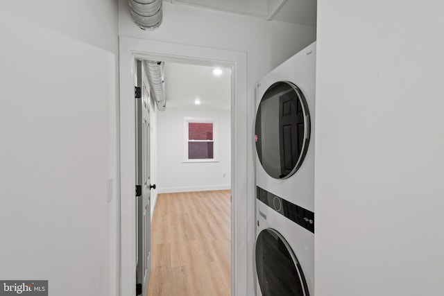 washroom featuring stacked washer / drying machine and light hardwood / wood-style flooring