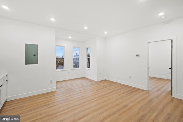 spare room featuring electric panel and light hardwood / wood-style floors