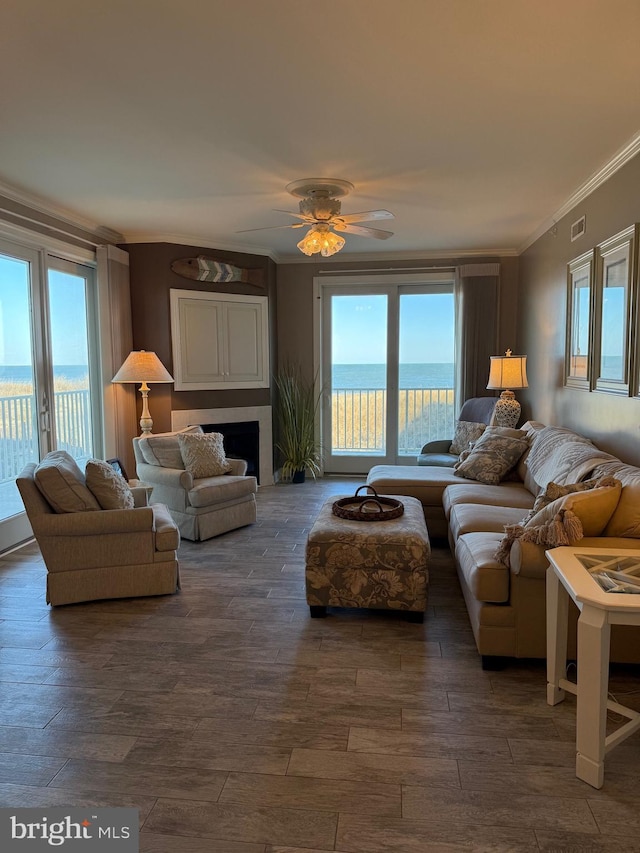 living room featuring ornamental molding, a water view, dark wood-type flooring, and ceiling fan