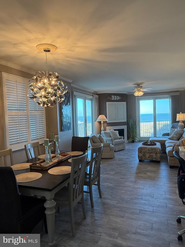 dining area with a water view, a wealth of natural light, dark wood finished floors, and crown molding