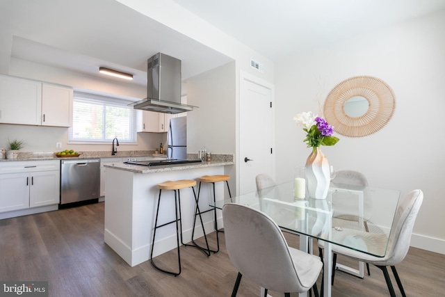 kitchen featuring island range hood, dark wood finished floors, light stone counters, stainless steel appliances, and white cabinetry