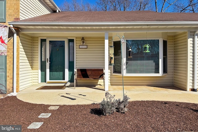 doorway to property with roof with shingles