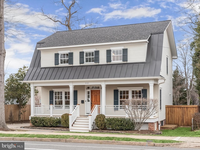 view of front of home featuring a standing seam roof, a porch, roof with shingles, and fence