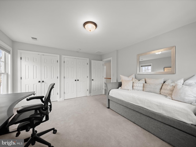 carpeted bedroom with multiple closets, visible vents, and baseboards