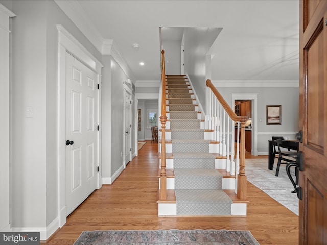 foyer entrance featuring baseboards, stairway, ornamental molding, light wood-style floors, and recessed lighting