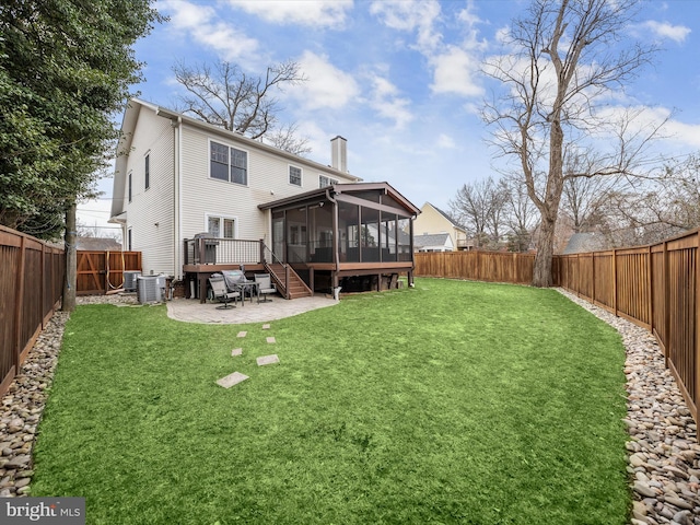 back of house featuring a patio, a fenced backyard, a sunroom, a lawn, and a chimney