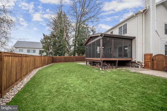 view of yard featuring a sunroom, a gate, and a fenced backyard