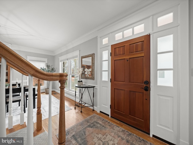 entryway with crown molding, baseboards, and wood finished floors