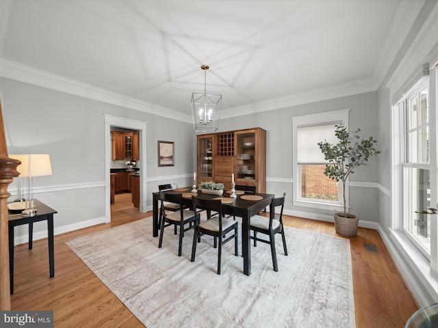 dining room featuring visible vents, ornamental molding, light wood-style flooring, and a notable chandelier