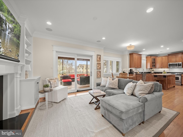 living area with light wood-type flooring, ornamental molding, and recessed lighting