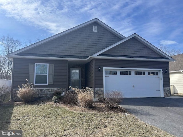 view of front of property with aphalt driveway, stone siding, and an attached garage