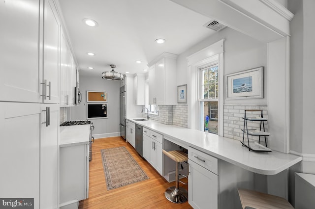 kitchen featuring appliances with stainless steel finishes, a breakfast bar, light countertops, and white cabinets