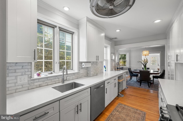 kitchen featuring decorative light fixtures, light countertops, white cabinets, a sink, and dishwasher